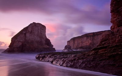 Purple sunset over the high rocky shore Wallpaper