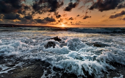 Waves reaching the rocky beach at sunset Wallpaper