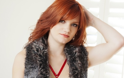 Redhead in a furry vest with a hand on her head wallpaper