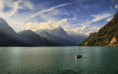 Lonesome small boat on the lake surrounded by the mountains wallpaper