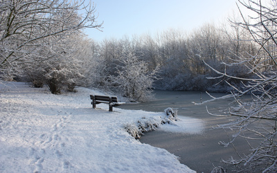 Snowy bench by the frozen river wallpaper