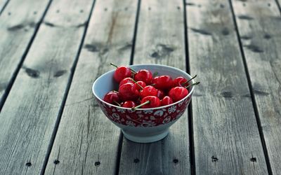 Cherries in a bowl on a wooden table wallpaper